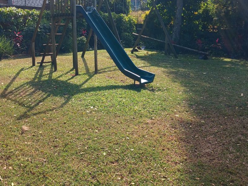 A private garden area featuring a lawn, mature trees, and perimeter fencing, providing a quiet outdoor space.