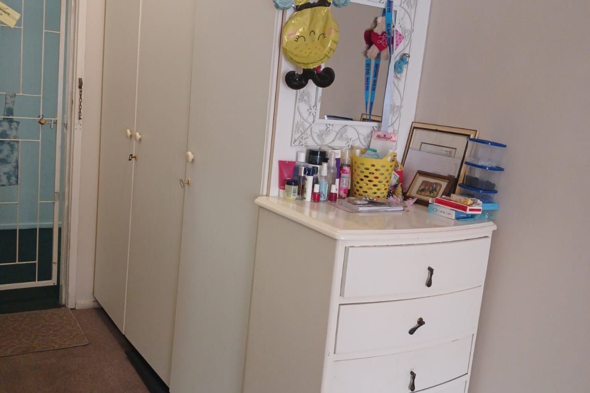 Bedroom featuring a tall built-in wardrobe and access to an adjacent area through a security gate.