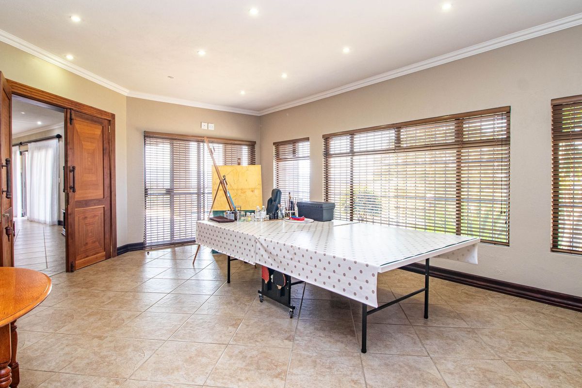 Spacious living area featuring tiled flooring, recessed downlights, and large windows fitted with wooden venetian blinds, offering a bright and versatile living space.