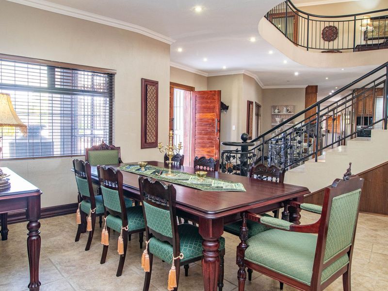 Spacious dining area featuring tiled flooring, recessed lighting, and an elegant wrought iron staircase leading to the upper level.