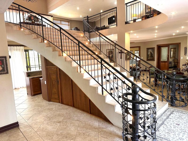 Grand entrance hall featuring a prominent staircase with decorative wrought iron railings, tiled flooring, and integrated under-stair storage cabinetry.