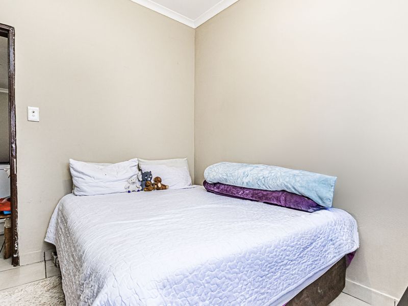A compact bedroom featuring neutral wall tones, tiled flooring, and a simple cove cornice finish.