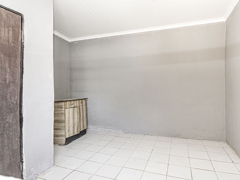 A simple, empty utility space featuring tiled flooring and a small built-in cabinet, offering a blank canvas for storage or functional use.