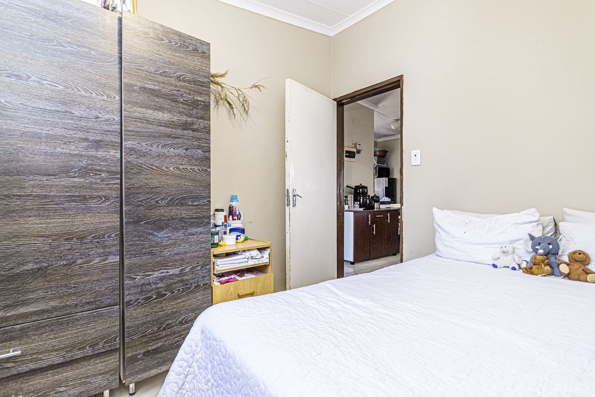 A standard bedroom featuring neutral wall finishes and coving, with an internal doorway providing access to an adjacent kitchen area.