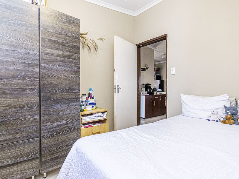 A standard bedroom featuring neutral wall finishes and coving, with an internal doorway providing access to an adjacent kitchen area.