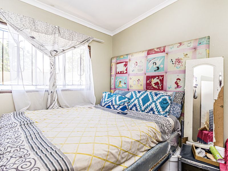 A standard bedroom featuring a window with security bars and coving, providing a functional space for rest.