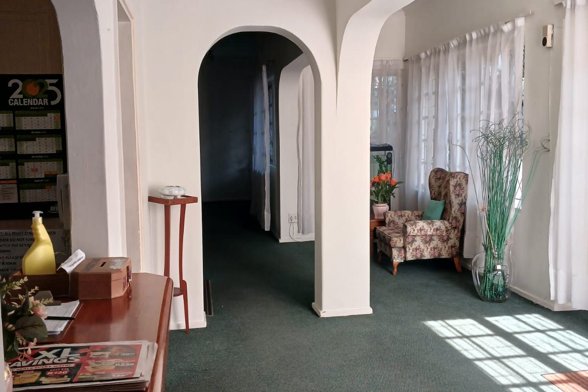 A living area featuring distinctive architectural archways, large windows allowing natural light, and carpeted flooring throughout the space.