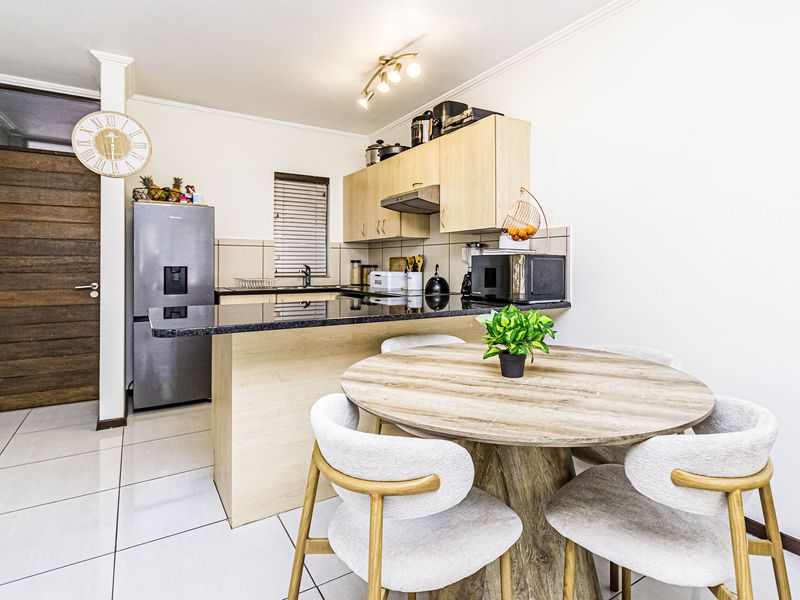 Open-plan kitchen featuring laminate cabinetry, granite countertops, and tiled flooring, seamlessly integrated with a dining area.