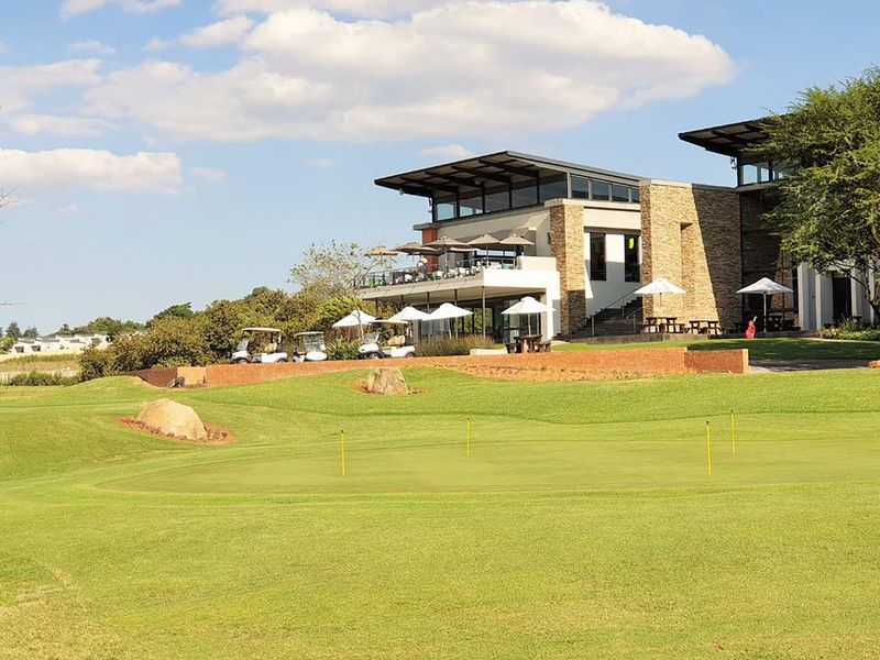 A view of the clubhouse building featuring stone cladding and a balcony overlooking the golf course green.