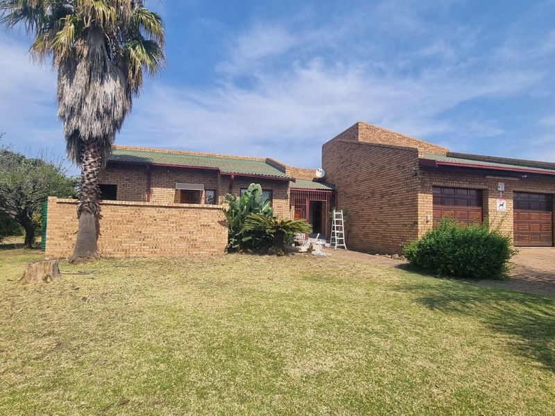 Front view of a face brick house featuring a double garage, paved driveway, and established garden area.