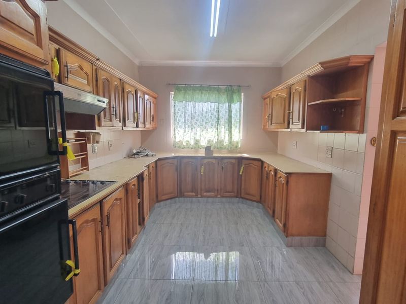 A functional kitchen featuring extensive built-in wooden cabinetry, laminate countertops, a built-in oven, and tiled flooring throughout.