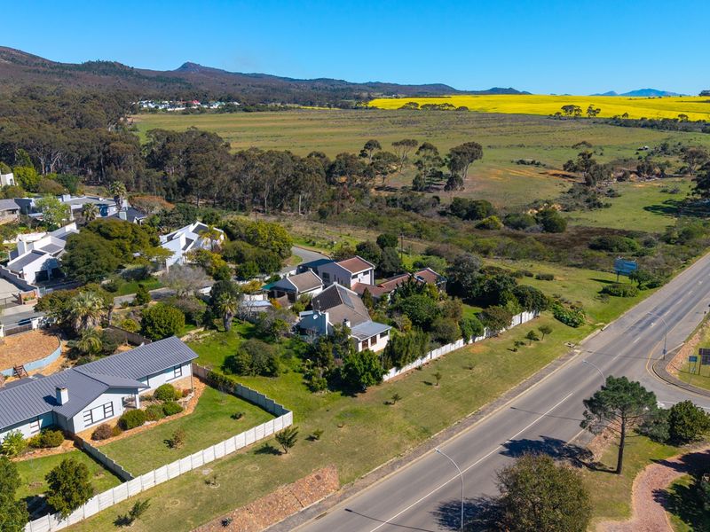 An aerial view of a residential neighborhood featuring established homes, paved roads, and expansive surrounding landscape with mountain views.