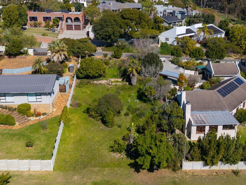 Aerial view of a vacant residential land plot situated within an established neighborhood, surrounded by existing homes and mature landscaping.