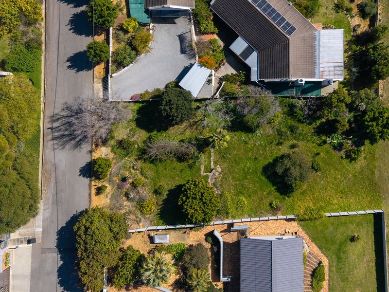 Aerial view of a residential property featuring a landscaped garden, paved driveway, and a main dwelling equipped with solar panels.