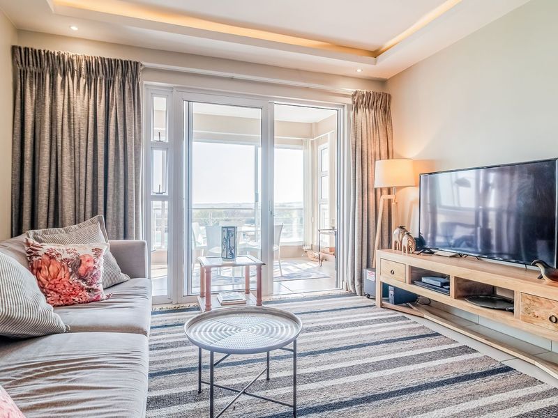 A bright and well-maintained living room featuring recessed ceiling lighting and large sliding glass doors that provide direct access to an outdoor balcony area.