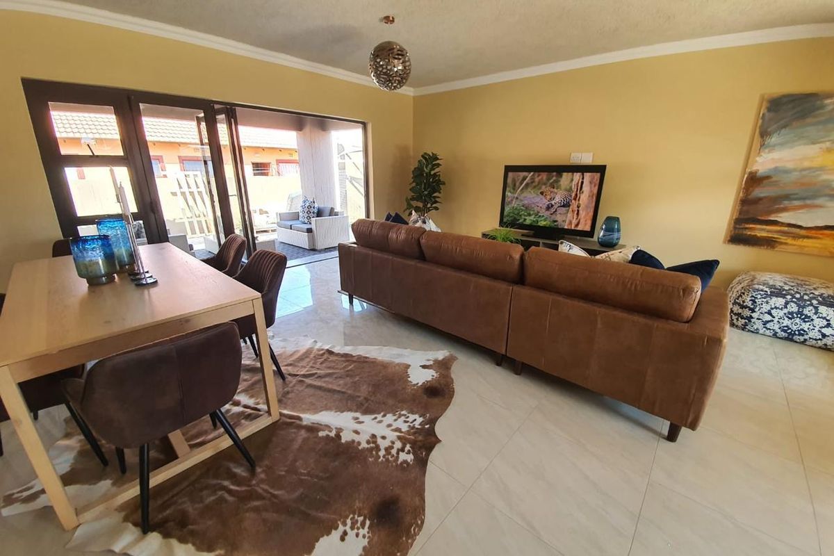 An open-plan living and dining area featuring tiled flooring and large sliding glass doors that provide seamless access to the outdoor patio space.