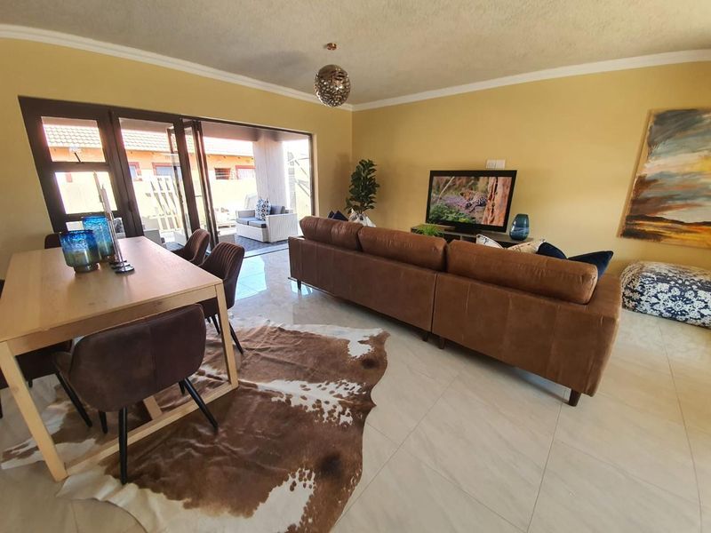 An open-plan living and dining area featuring tiled flooring and large sliding glass doors that provide seamless access to the outdoor patio space.