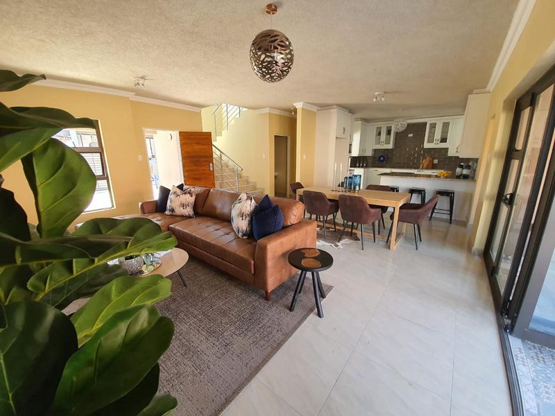 Spacious open-plan living and dining area featuring a modern kitchen with island, tiled floors, and a staircase leading to the upper level.