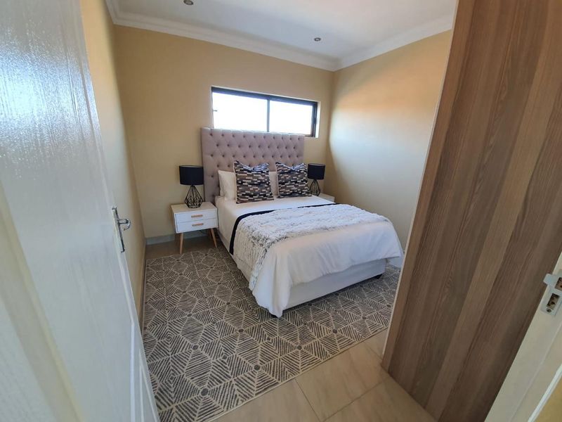 A well-maintained bedroom featuring tiled flooring, recessed downlighting, coving, and a built-in cupboard, offering a clean and functional living space.
