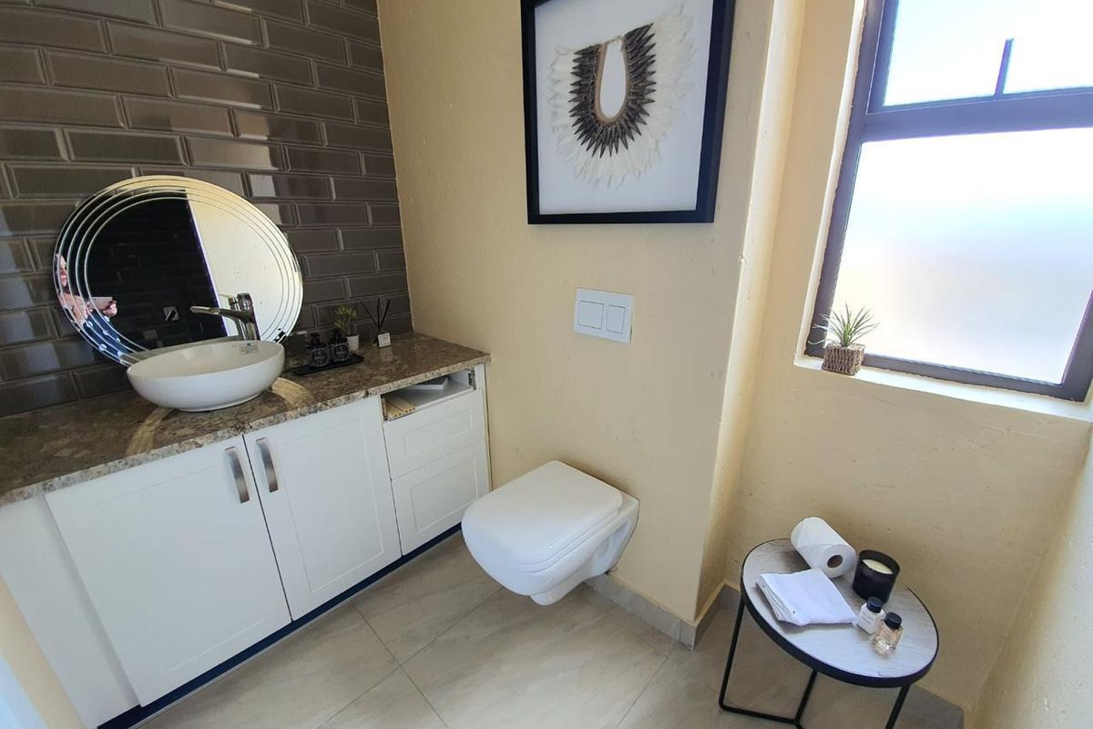 A modern bathroom featuring a wall-mounted toilet, a vanity cabinet with a stone countertop, and a stylish vessel sink with subway tile backsplash.