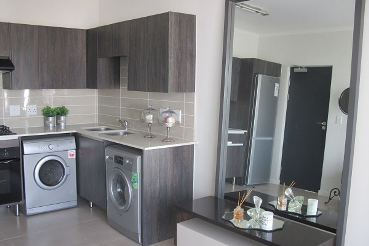 Modern kitchen featuring dark wood-grain cabinetry, stone countertops, subway tile backsplash, and integrated stainless steel appliances.