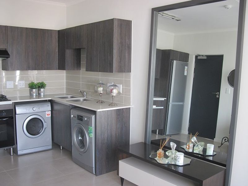Modern kitchen featuring dark wood-grain cabinetry, stone countertops, subway tile backsplash, and integrated stainless steel appliances.