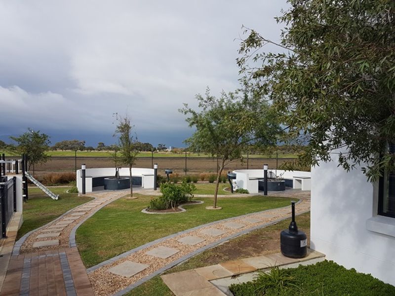 A well-maintained communal garden area featuring paved walkways, landscaped lawns, and built-in circular seating structures, providing an inviting outdoor space.