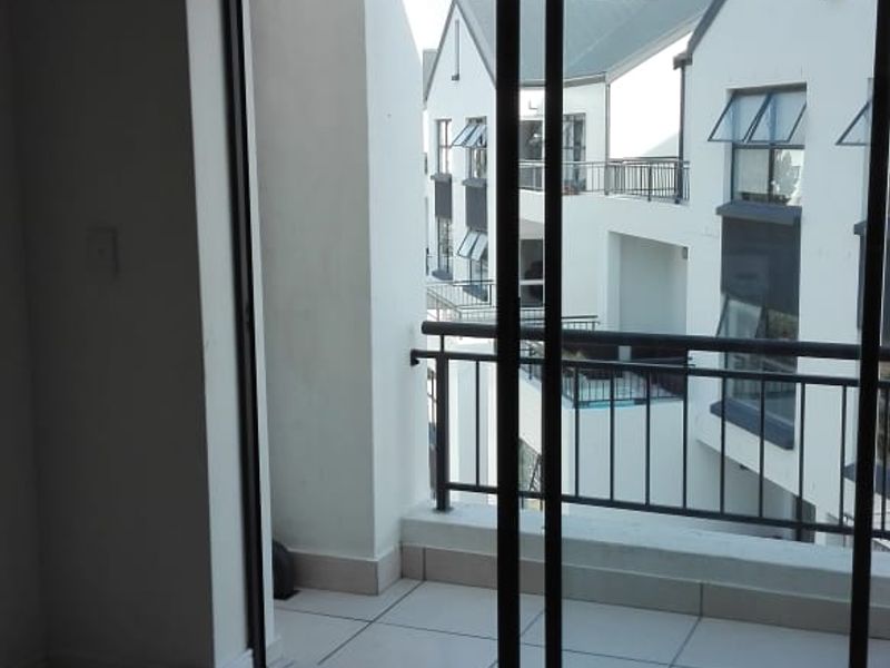 A clean, tiled balcony area accessible through sliding glass doors, offering a view of the surrounding apartment complex architecture.
