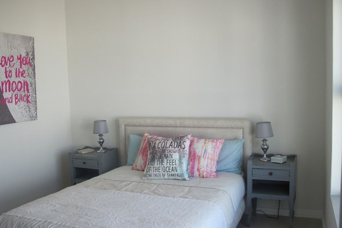 A neutrally painted bedroom featuring tiled flooring and a window, providing a clean and simple space for rest.