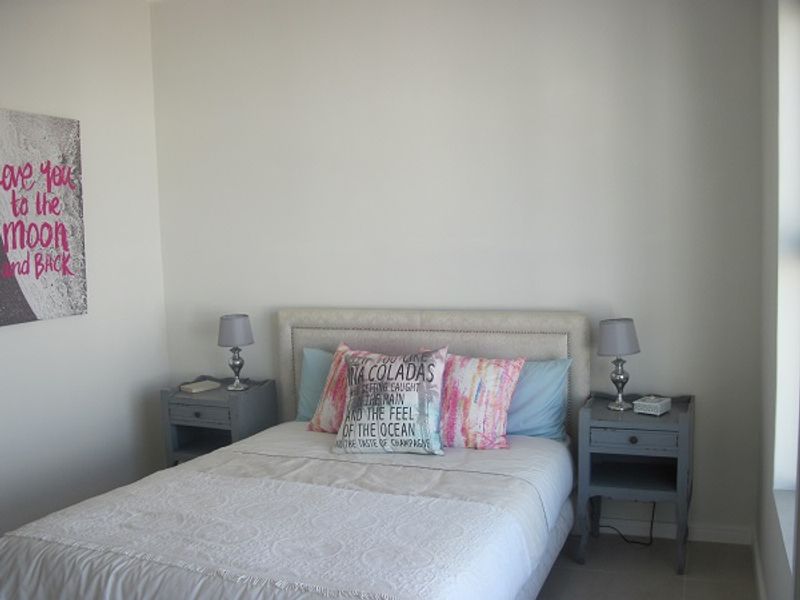 A neutrally painted bedroom featuring tiled flooring and a window, providing a clean and simple space for rest.