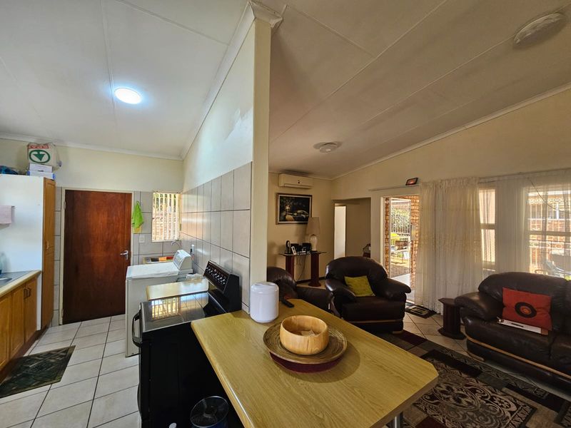 Open-plan living and kitchen area featuring tiled flooring, built-in cabinetry, a stove, and direct access to an outdoor patio area.