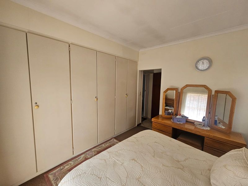 A bedroom featuring extensive floor-to-ceiling built-in cupboards and coved ceiling detailing, offering ample storage space.