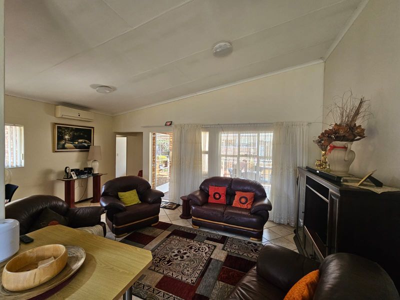 Spacious living room featuring tiled flooring, a split-system air conditioner, and direct access to an outdoor patio area through sliding glass doors.