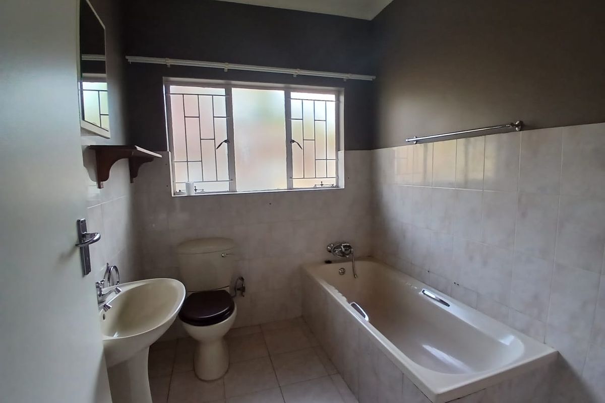 A functional bathroom featuring a pedestal basin, toilet, and bathtub with tiled walls and flooring, ready for modernization.
