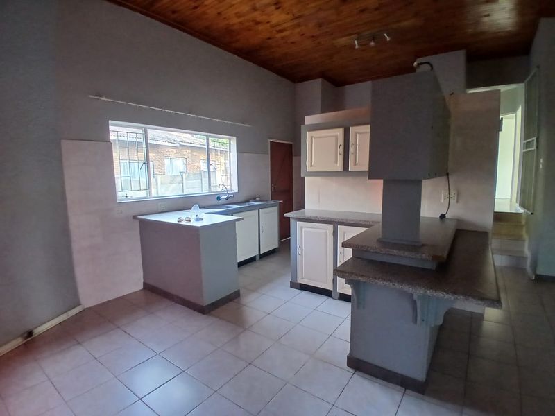 A functional kitchen featuring built-in cabinetry, a breakfast bar, tiled flooring, and a timber ceiling, offering a blank canvas for modern updates.