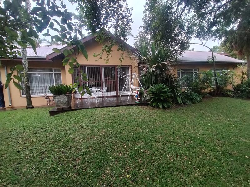 Rear view of the house featuring a timber deck, sliding glass doors, and a well-maintained garden area.