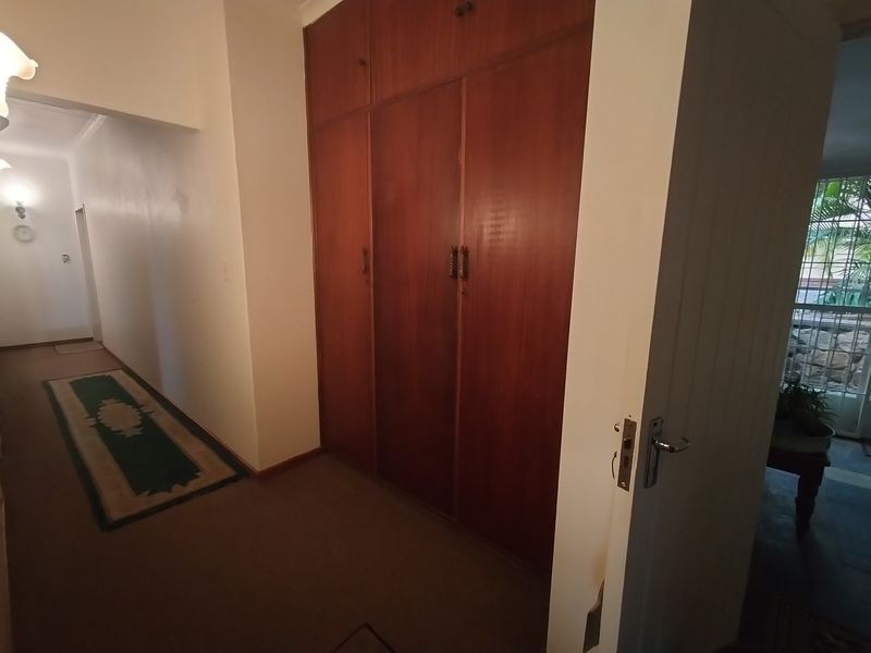 A hallway featuring built-in wooden storage cupboards and access to an exterior security gate.