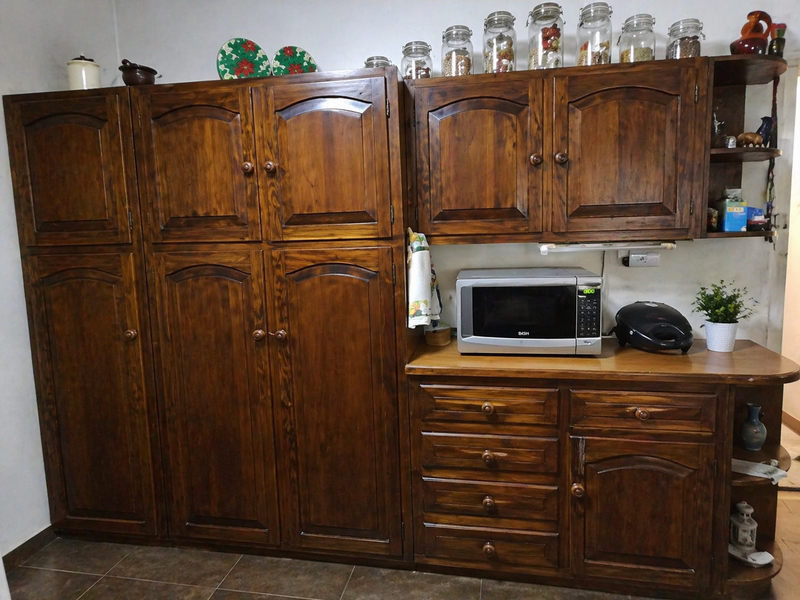 A kitchen area featuring extensive built-in dark wood cabinetry, drawers, and a wooden countertop with an integrated microwave.