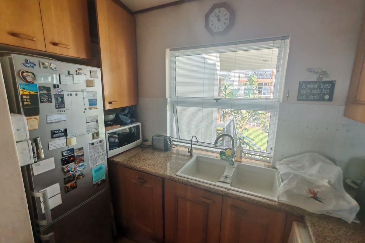 A functional kitchen featuring wooden cabinetry, granite countertops, and a double basin sink with a window view.