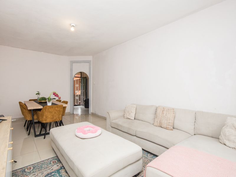Open plan living and dining area featuring tiled flooring and an arched doorway leading to the entrance.