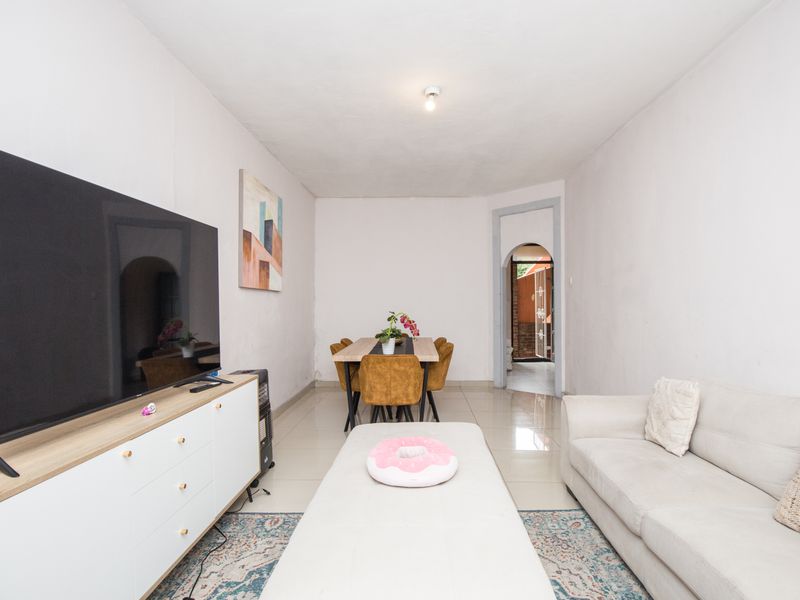 Open plan living and dining area featuring tiled flooring and an arched doorway leading to the exterior.