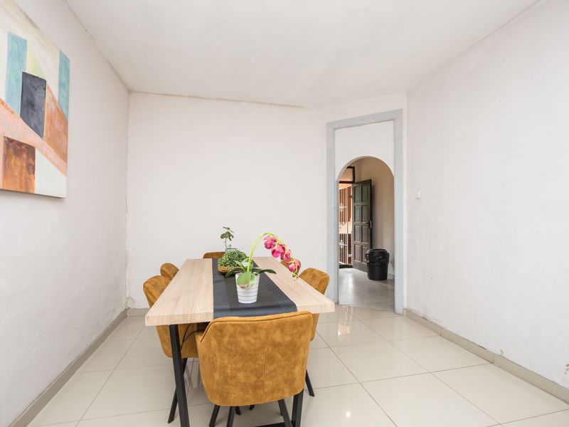 A simple dining area featuring light-colored tiled flooring and a distinctive arched doorway leading to an adjacent space.