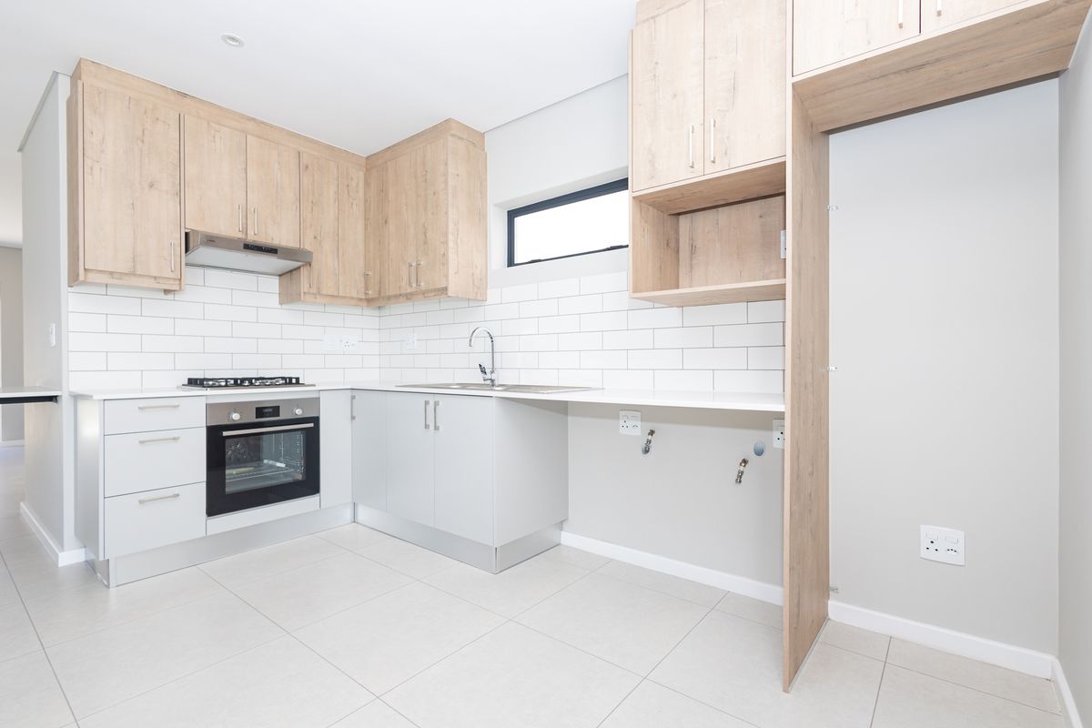 Modern kitchen featuring light wood-look cabinetry, subway tile backsplash, built-in oven, gas hob, and dedicated plumbing connections for appliances.