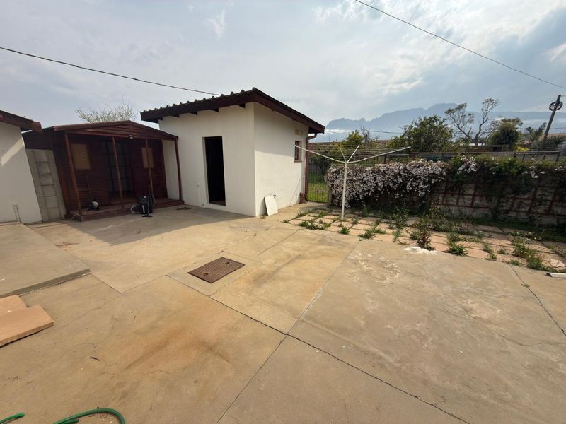 Rear exterior area featuring a concrete patio, an outbuilding, and a timber-framed structure, offering potential for landscaping and outdoor living space development.