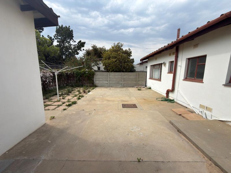 A paved rear courtyard area featuring a precast boundary wall and a rotary clothesline, offering a functional outdoor space with potential for landscaping.