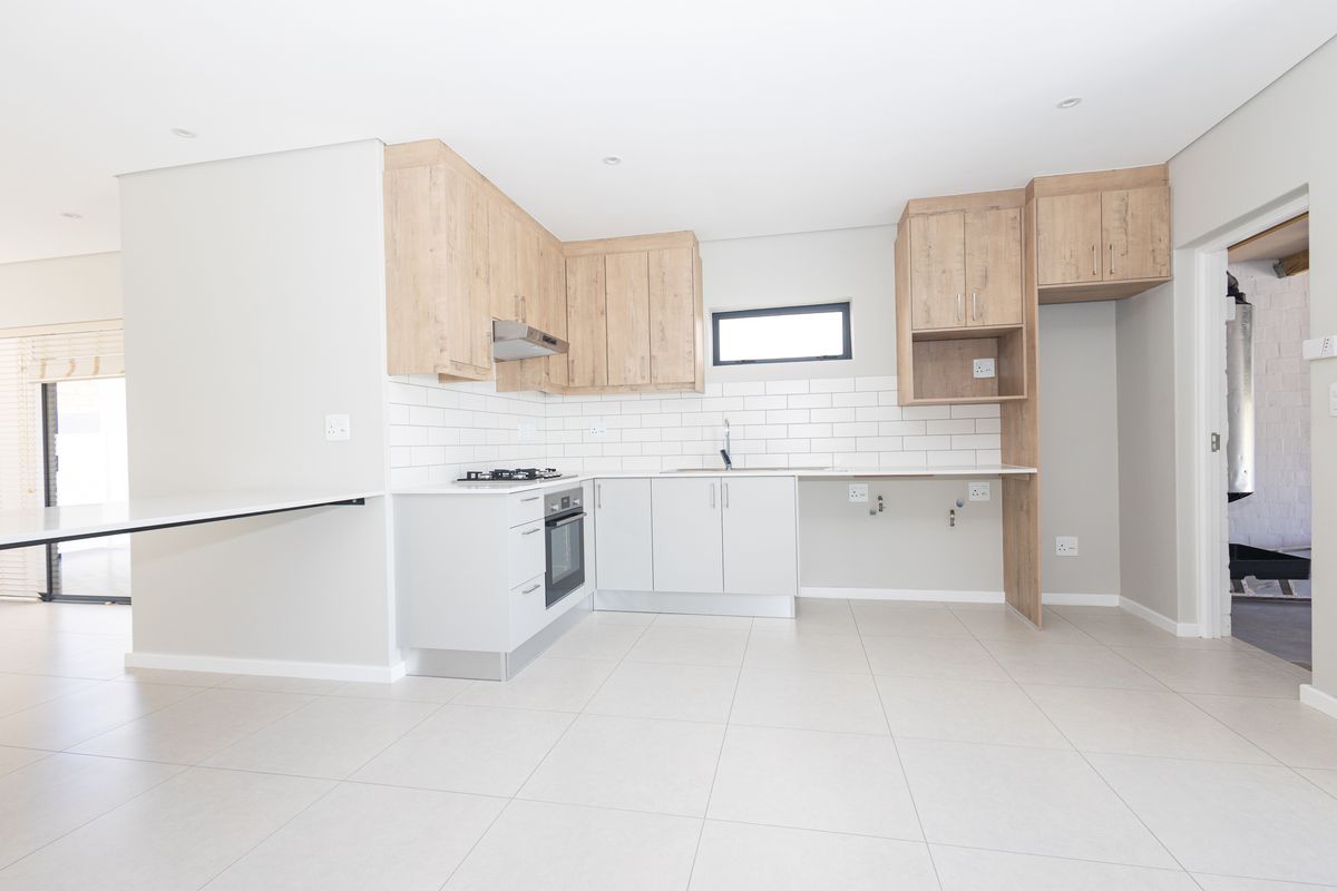 Modern kitchen featuring light wood and white cabinetry, subway tile backsplash, built-in oven, gas hob, and tiled flooring in a clean, open-plan layout.