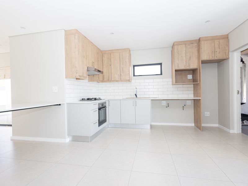 Modern kitchen featuring light wood and white cabinetry, subway tile backsplash, built-in oven, gas hob, and tiled flooring in a clean, open-plan layout.