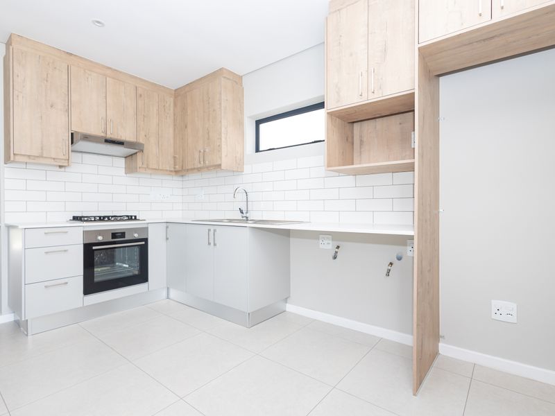 Modern kitchen featuring light wood-look cabinetry, subway tile backsplash, built-in oven, gas hob, and tiled flooring in a clean, contemporary finish.