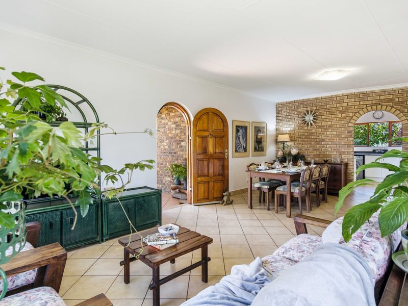 Spacious open-plan living and dining area featuring exposed brick walls, arched architectural details, and neutral ceramic floor tiling.