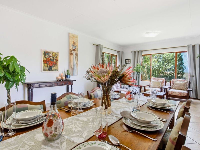An open-plan living and dining area featuring tiled flooring, large windows providing natural light, and a coved ceiling.